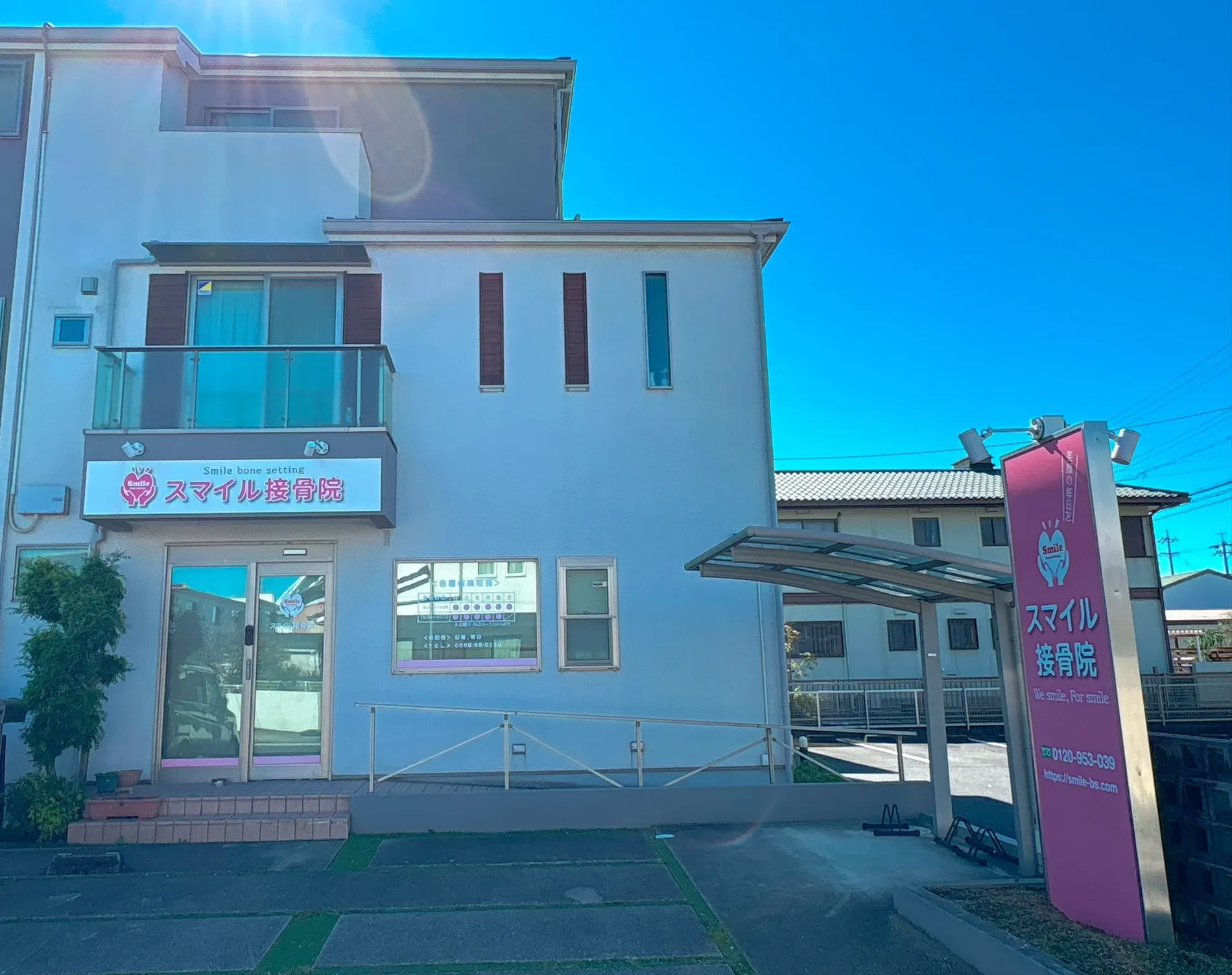 スマイル接骨院の外観とピンクの看板